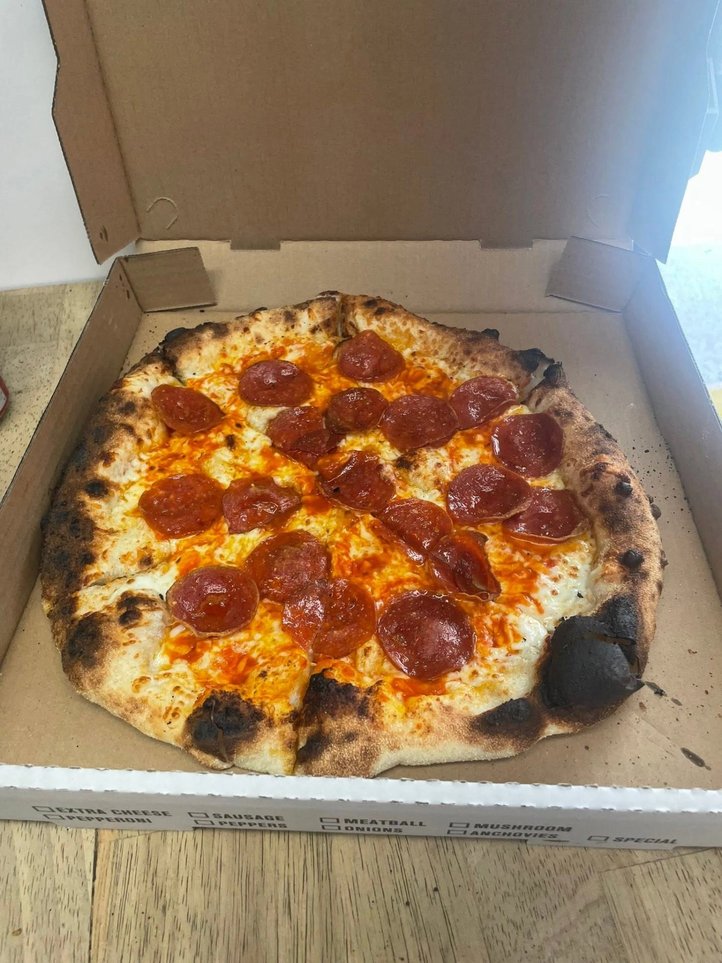 A classic cup-and-char pepperoni pie boxed and ready to eat